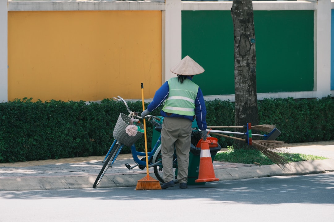 a-street-sweeper-stands-near-their-bicycle-kh7hfrxzmge